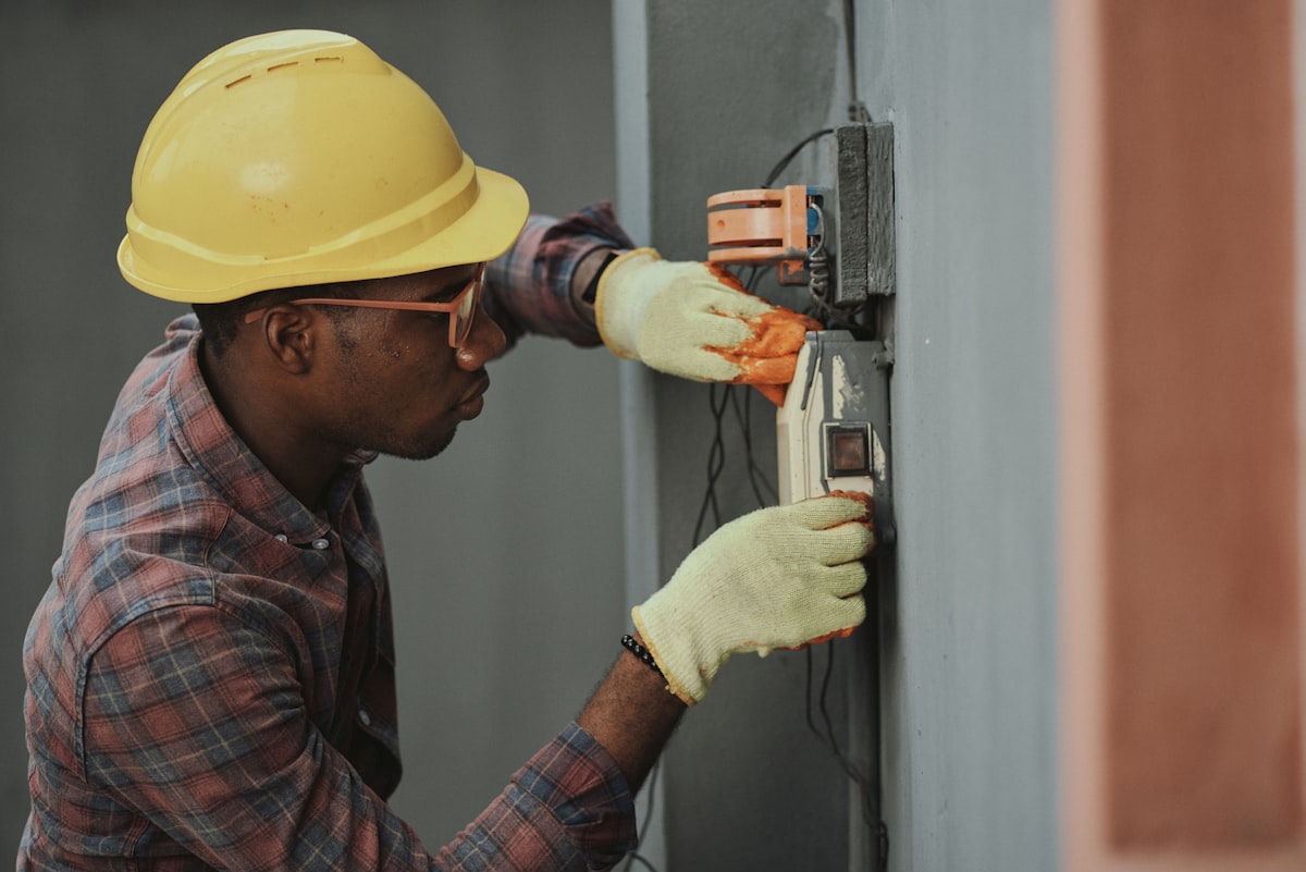 Electrician working on electrical panel with safety equipment